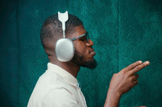 pexels-photo-30929638-30929638 A man wearing stylish headphones and sunglasses in a teal room, capturing modern music vibes.